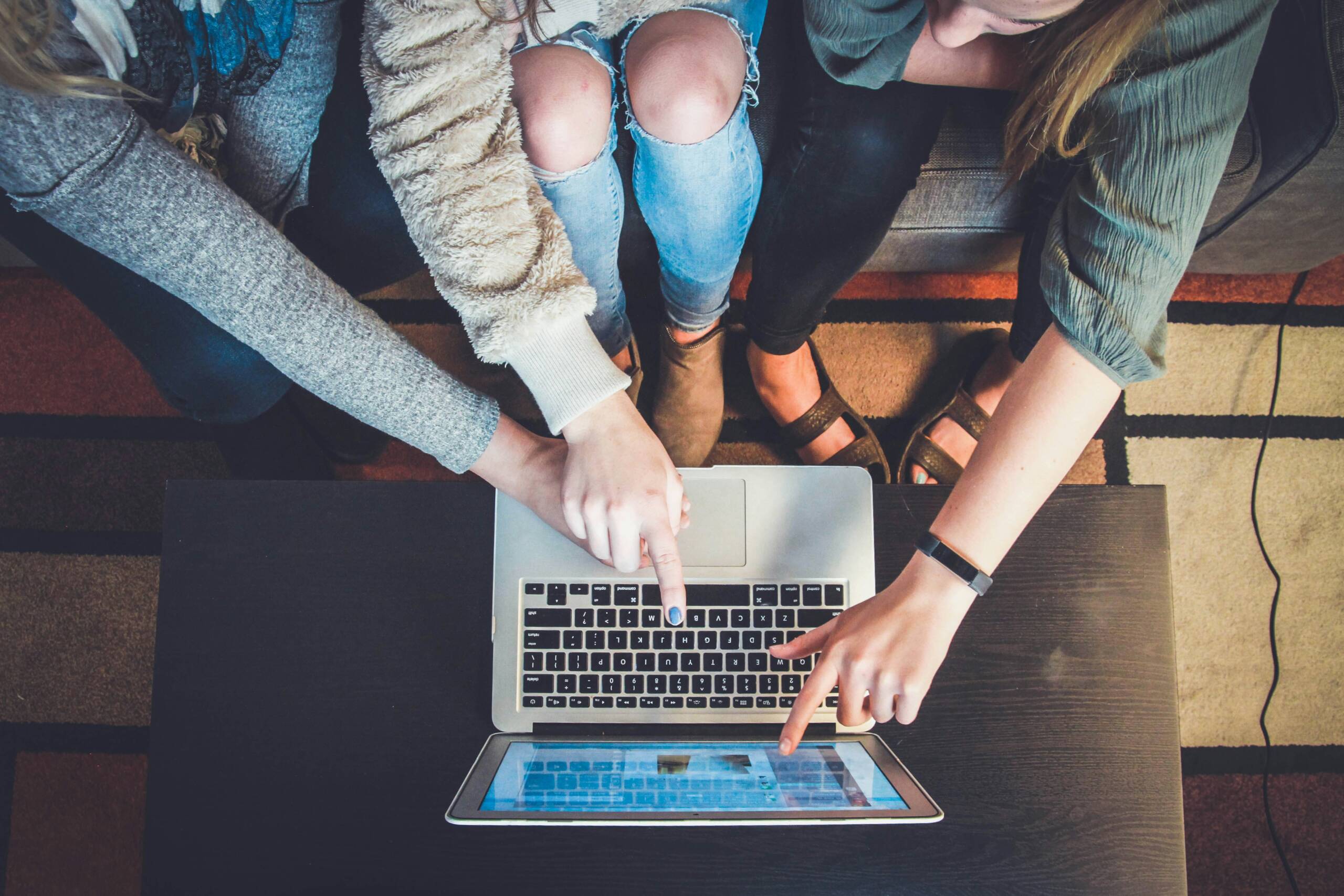 Kilka osób wskazujących coś na ekranie laptopa